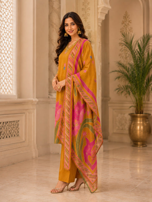 Woman wearing a mustard yellow kurta set with floral prints and palazzo pants, draped with a printed dupatta.