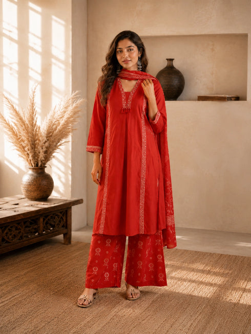 Woman wearing a rust-colored printed cotton kurti and pants set with intricate border details.