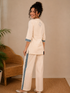 Woman wearing a cream kurta with blue paisley print, showcasing intricate embroidery and a band collar neckline.