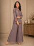 Woman wearing a pink embroidered choker neck Sharara with floral details on sleeves and hem.