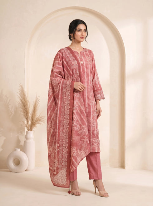 Woman wearing a rose pink printed kurti set with a dupatta, featuring leaf motifs and striped patterns.