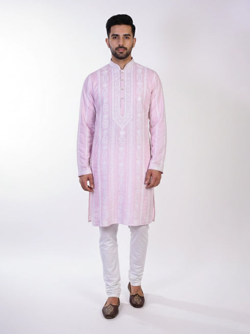 Man wearing a pink chikankari kurta with white churidar pants and brown embellished juttis.