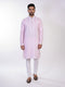 Man wearing a pink chikankari kurta with white churidar pants and brown embellished juttis.