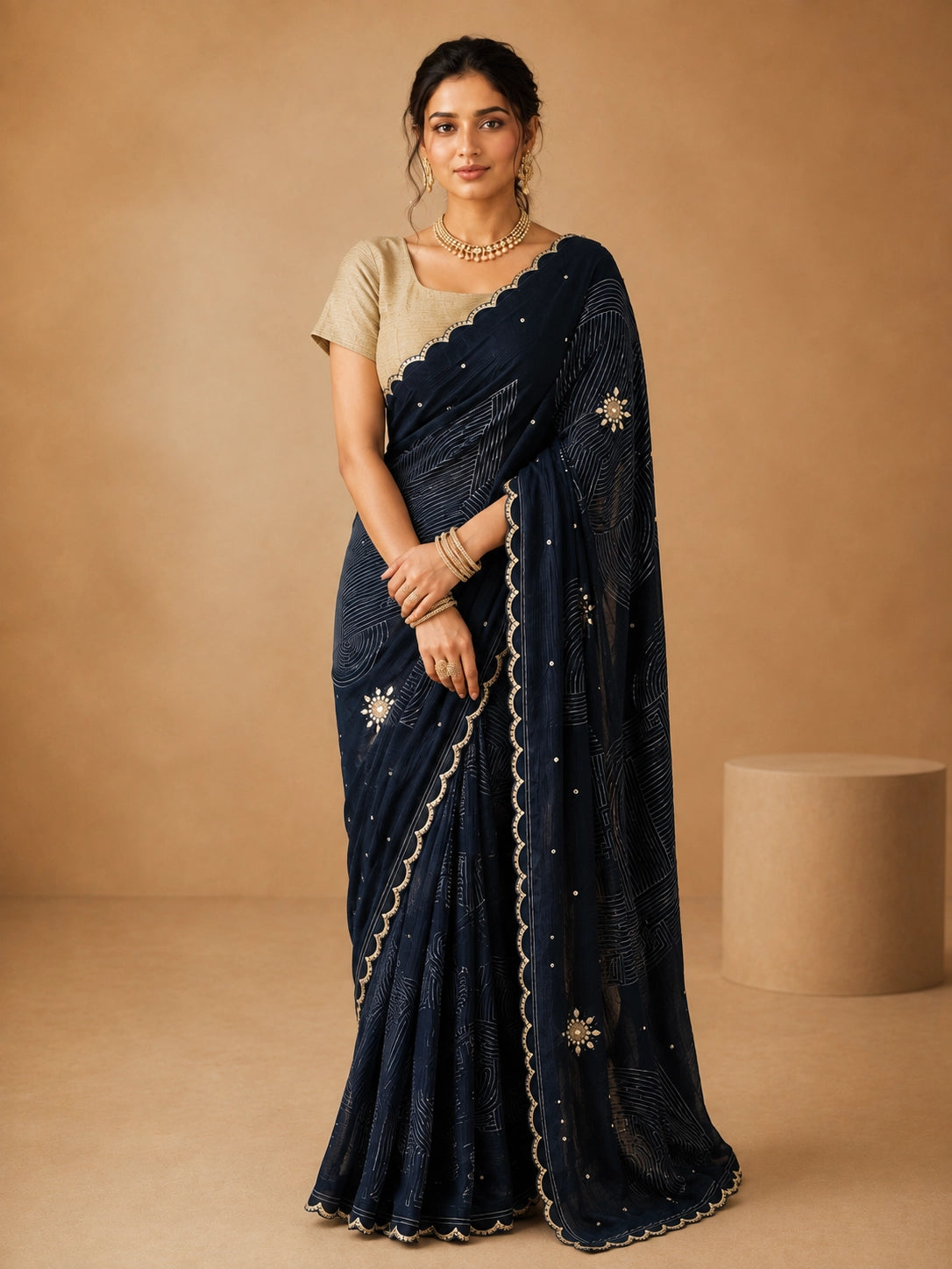 Woman wearing an elegant navy blue embroidered saree with a golden blouse and traditional jewelry.