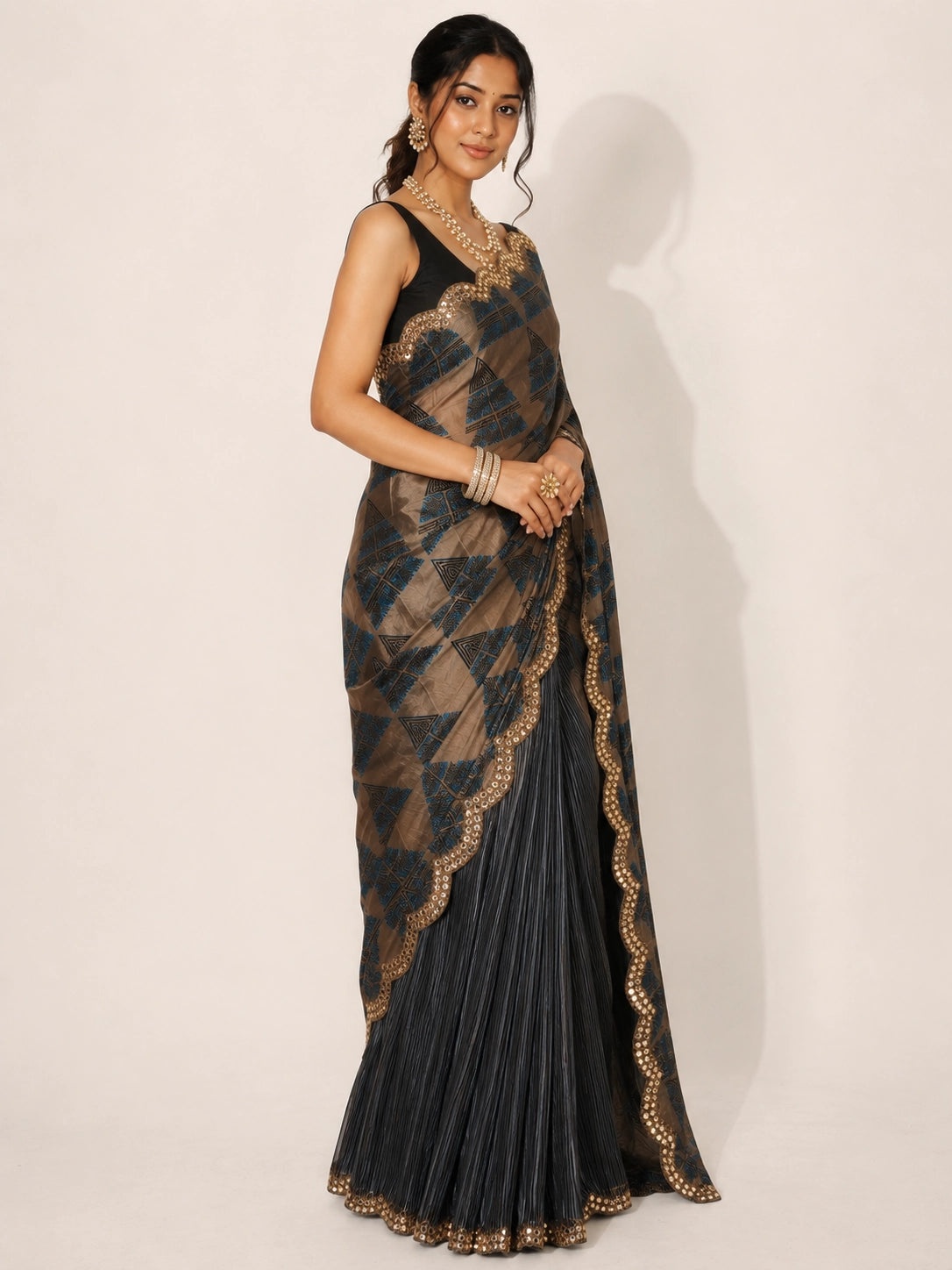 Woman in elegant grey and bronze  saree with geometric patterns and embellished border.