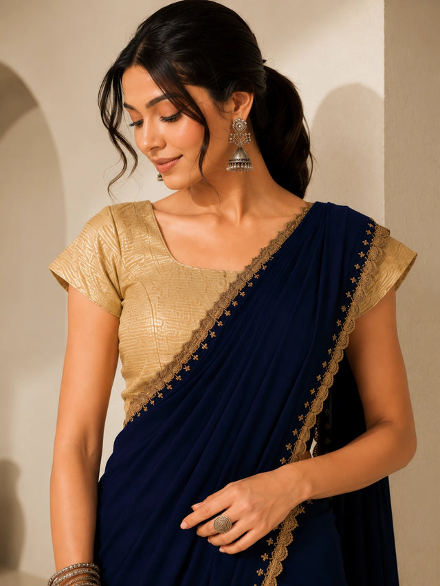 Woman wearing a navy blue saree with gold embroidered borders and a gold blouse.