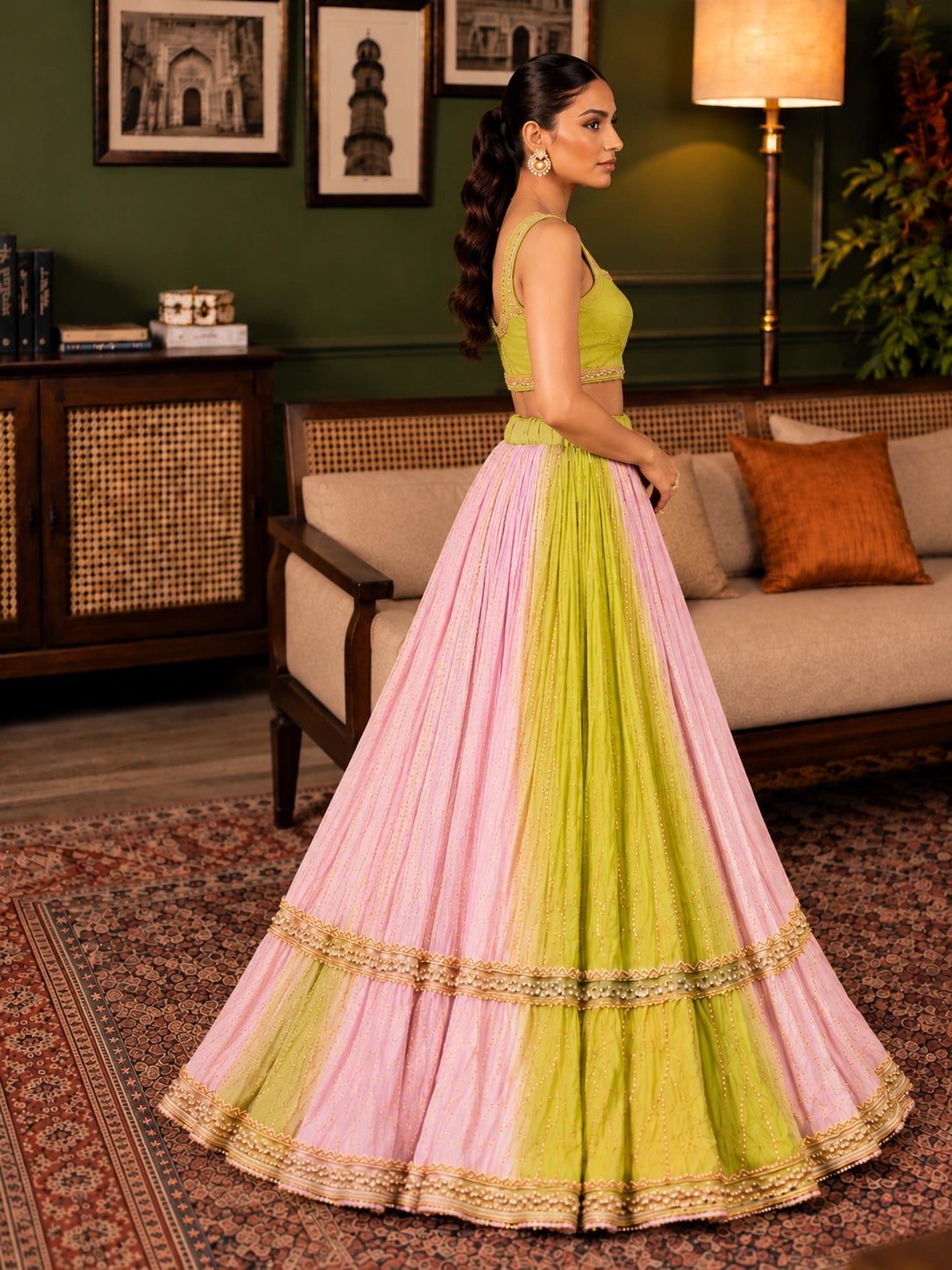 Elegant woman wearing a pink and green  lehenga choli with gold embroidery.