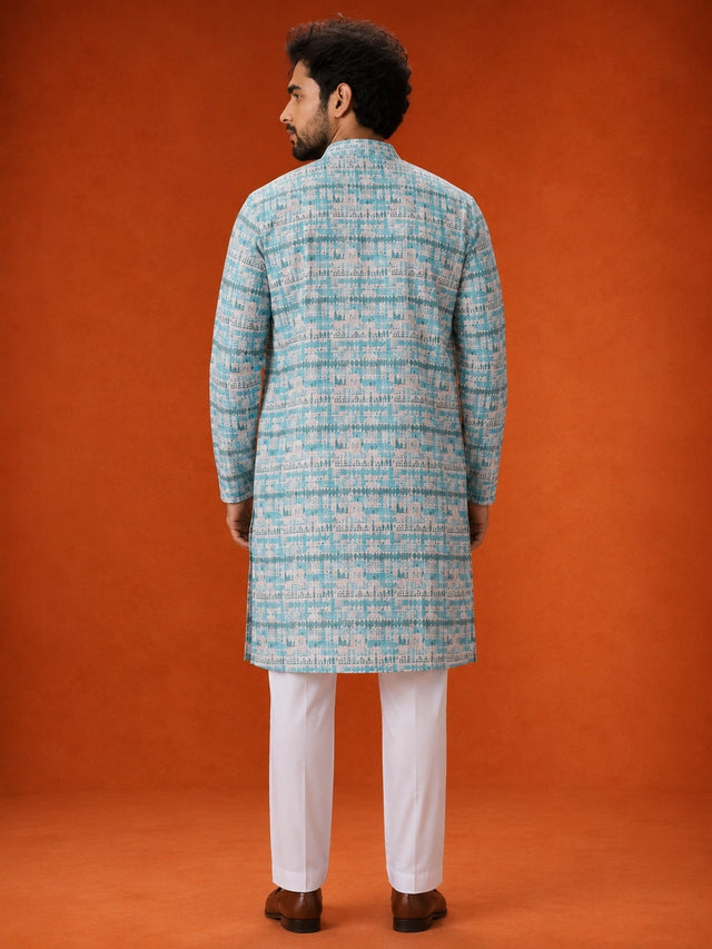 Man wearing an aqua and white printed kurta with white pajamas and brown loafers.