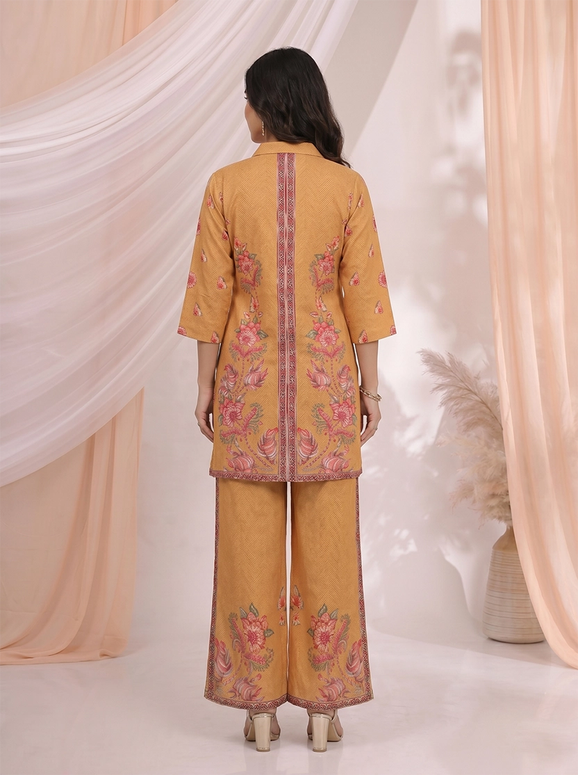 Woman wearing an ochre yellow kurta and palazzo set with a vibrant floral print.