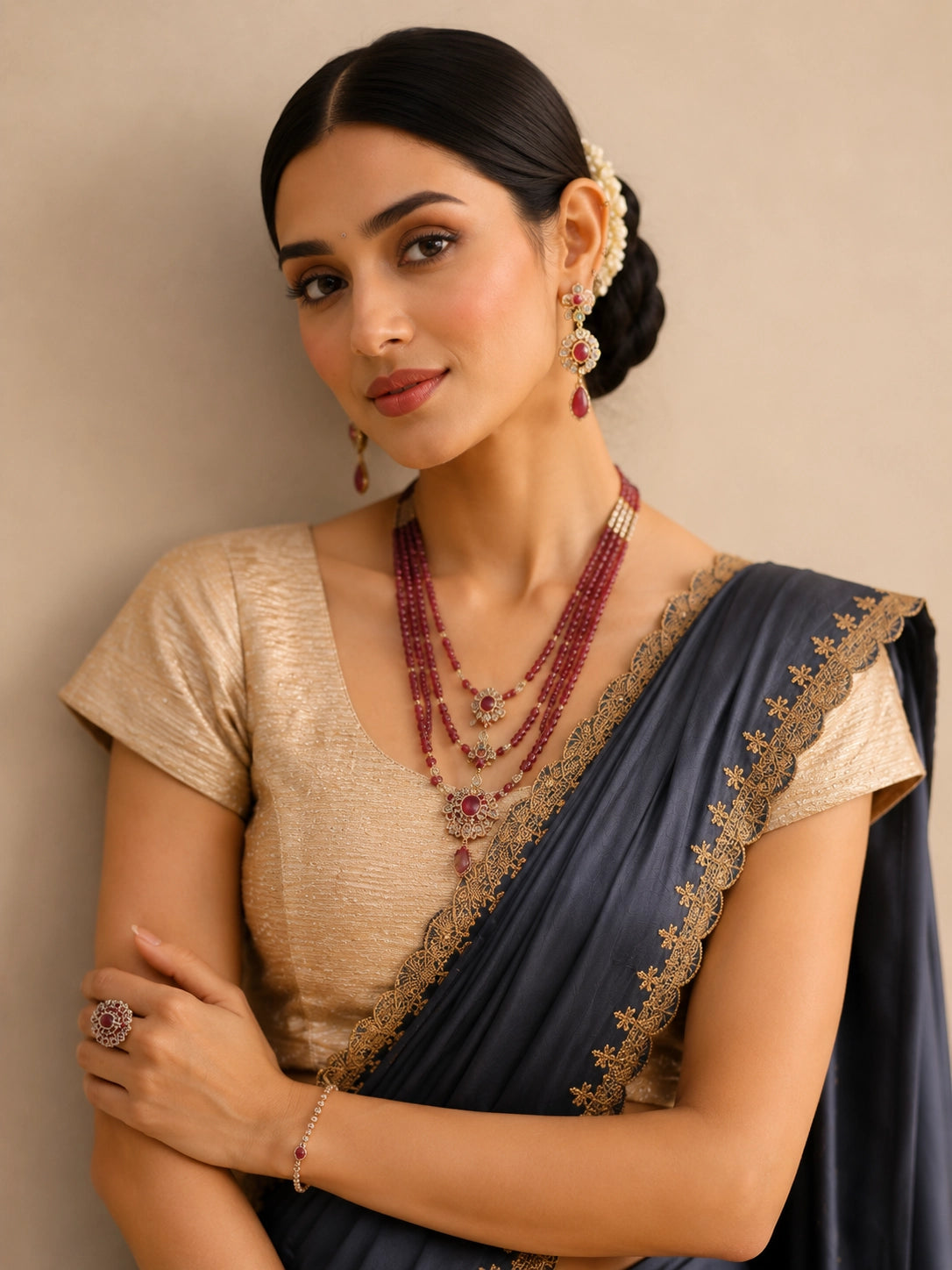 Woman wearing a flowing grey saree with an intricate golden border and a textured golden blouse.