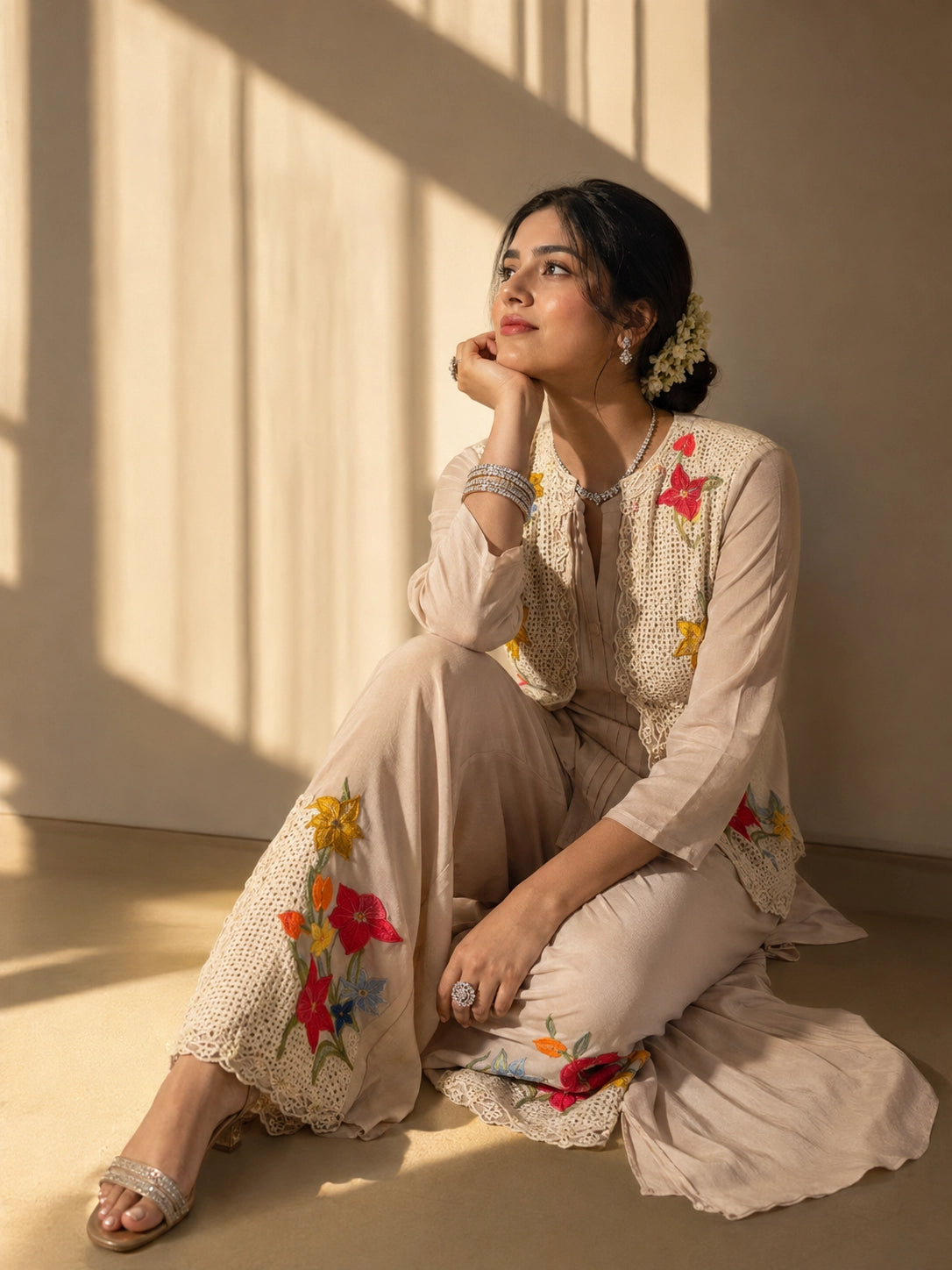 Woman in a beige kurta set with a short floral embroidered jacket and palazzo pants.