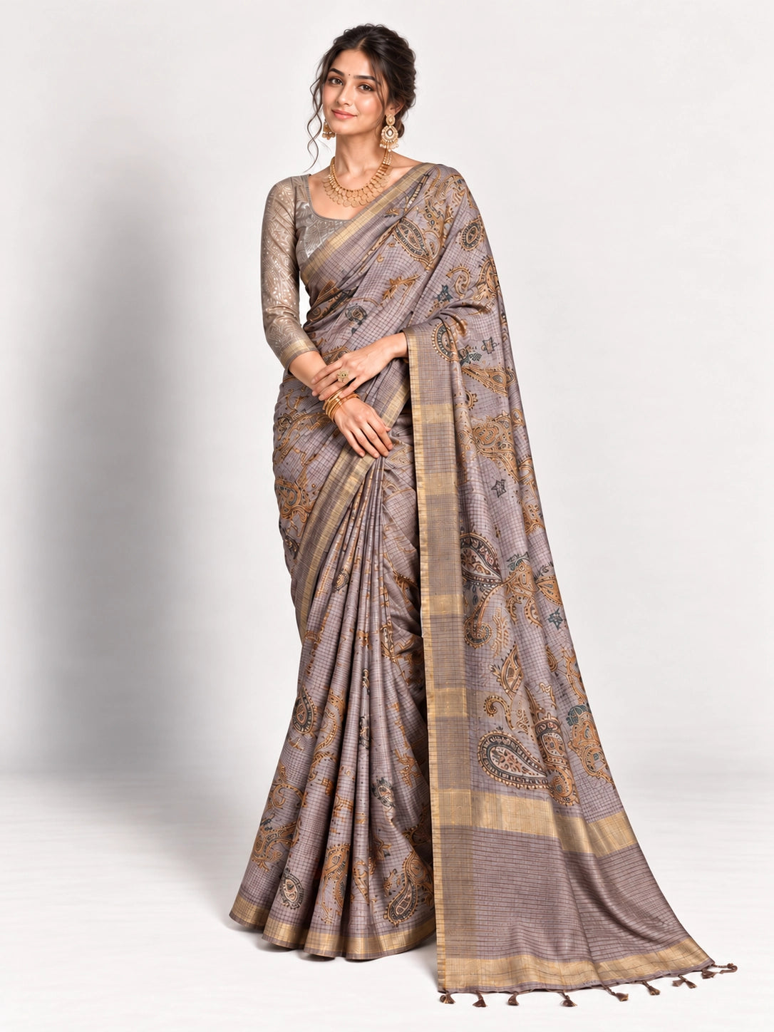 Woman in an elegant lavender grey saree with gold border and intricate paisley patterns.
