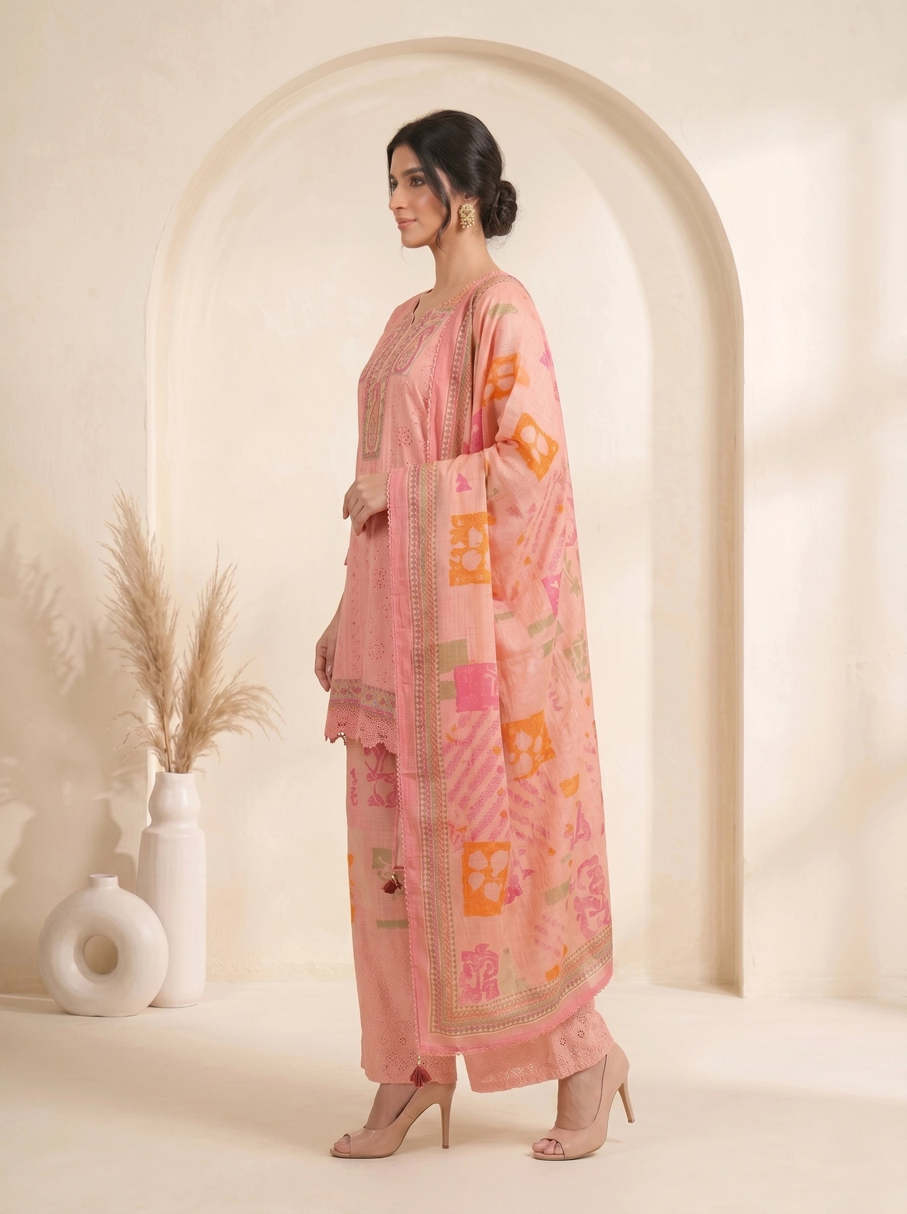 Woman wearing a pink printed cotton kurti set with palazzo pants and a dupatta, featuring eyelet details and block prints.