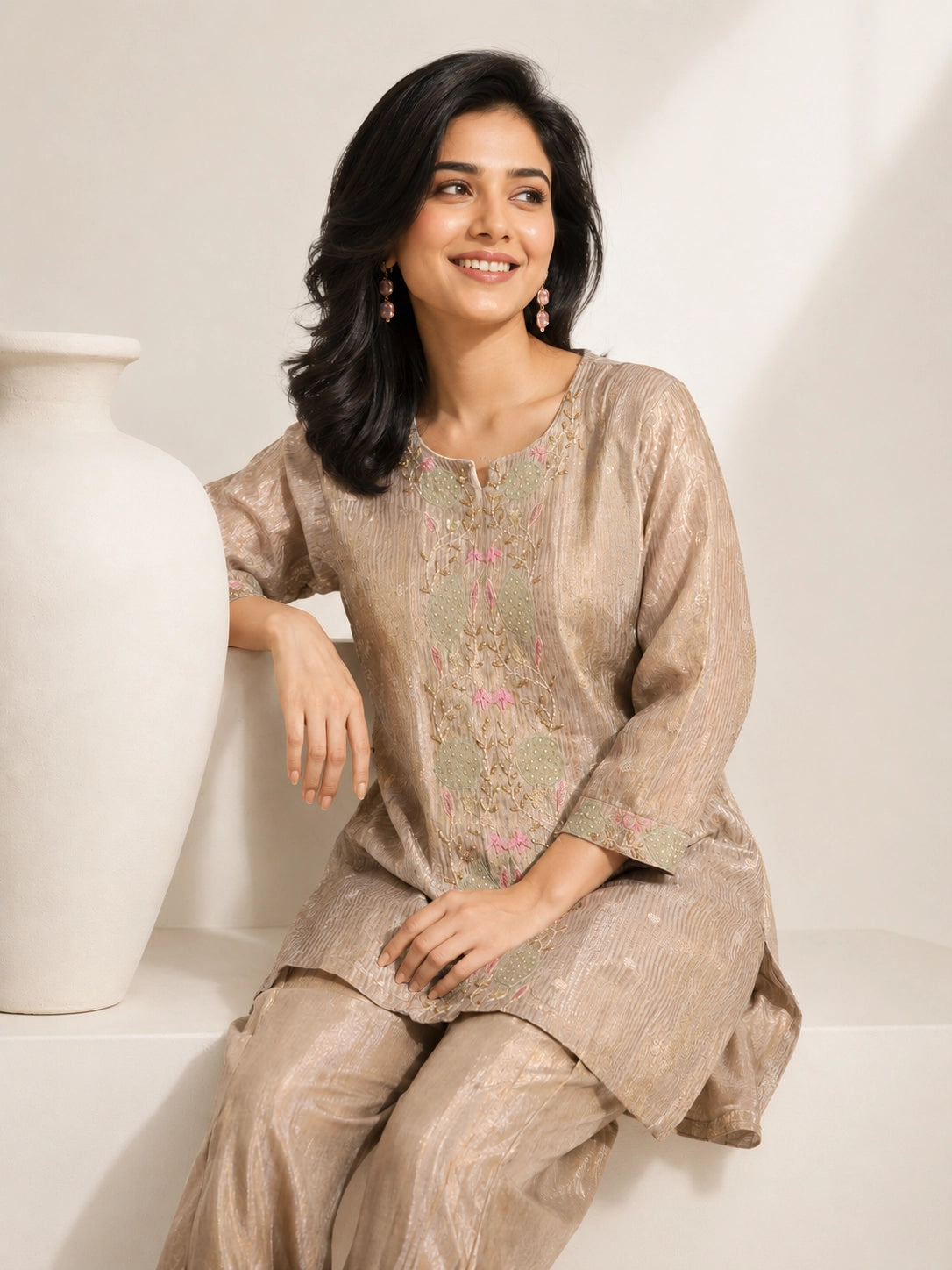 Woman wearing a shimmering grey embroidered kurta and matching pants, styled for a festive occasion.