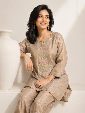 Woman wearing a shimmering grey embroidered kurta and matching pants, styled for a festive occasion.