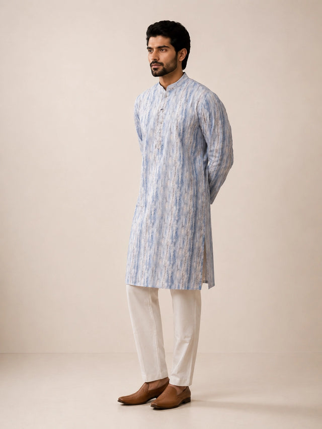 Man in a dust blue printed kurta, white pajama, and brown loafers.