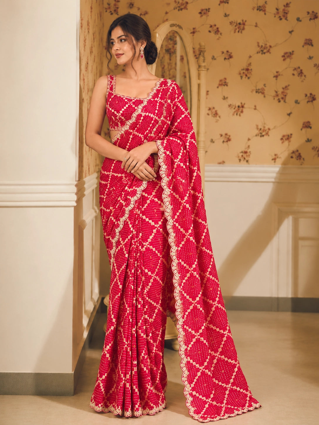 Woman in a vibrant red Bandhani saree with white patterns and scalloped border.