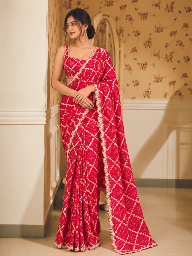 Woman in a vibrant red Bandhani saree with white patterns and scalloped border.