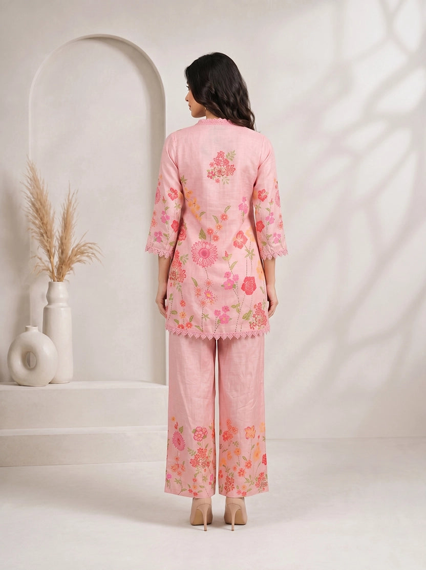 Woman wearing a pink floral print kurta with matching palazzo pants and lace trim.