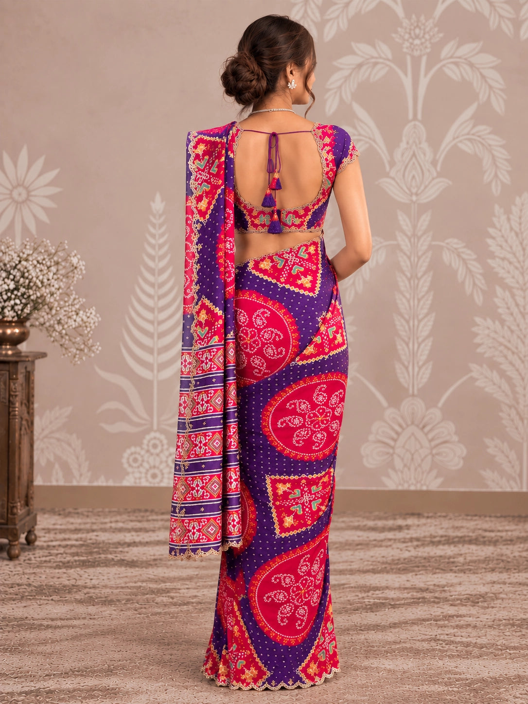 Woman in vibrant purple and pink printed saree with intricate patterns and scalloped border.