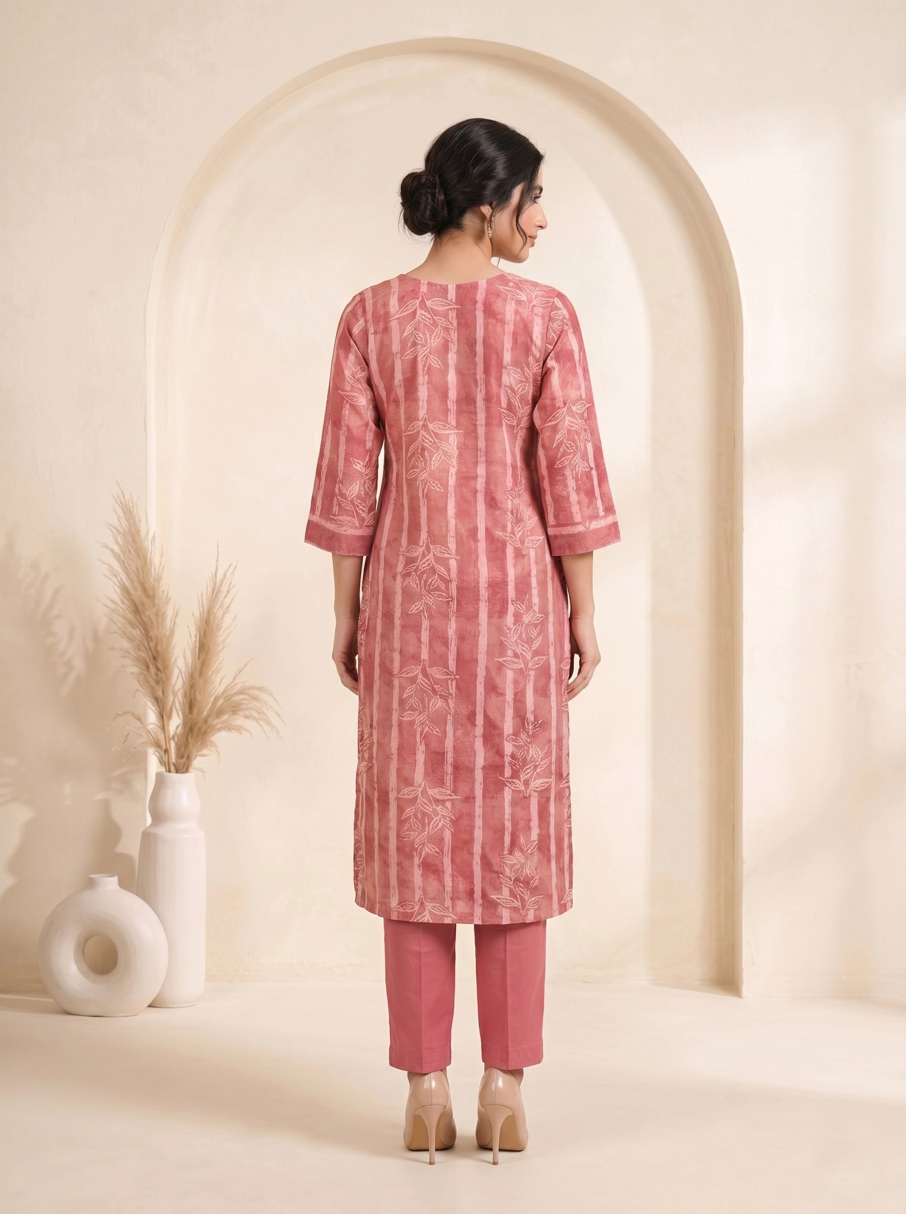 Woman wearing a rose pink printed kurti set with a dupatta, featuring leaf motifs and striped patterns.