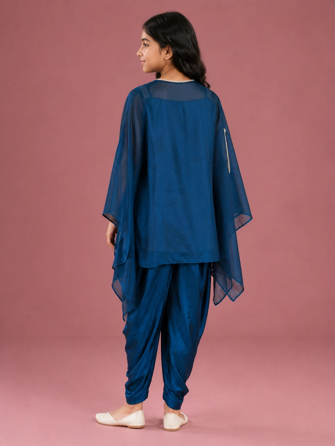 Young girl wearing a vibrant blue dhoti set with an embellished top and sheer jacket.