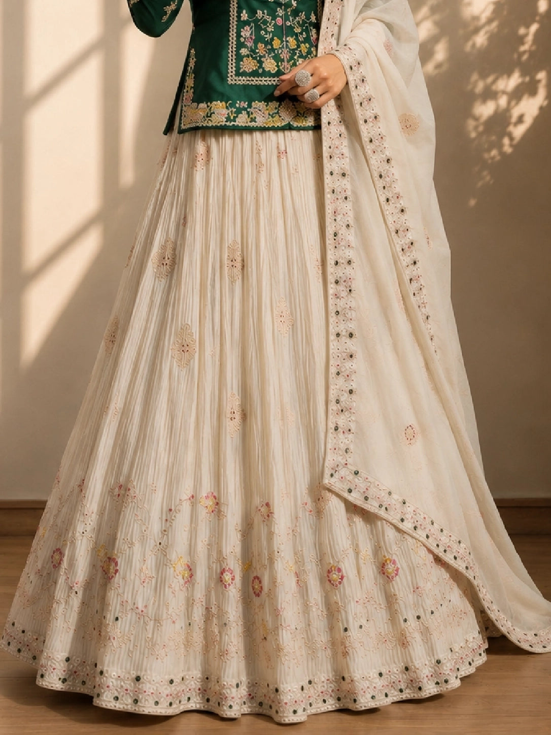 Elegant woman in a dark green embroidered kurta, cream pleated skirt, and matching dupatta.