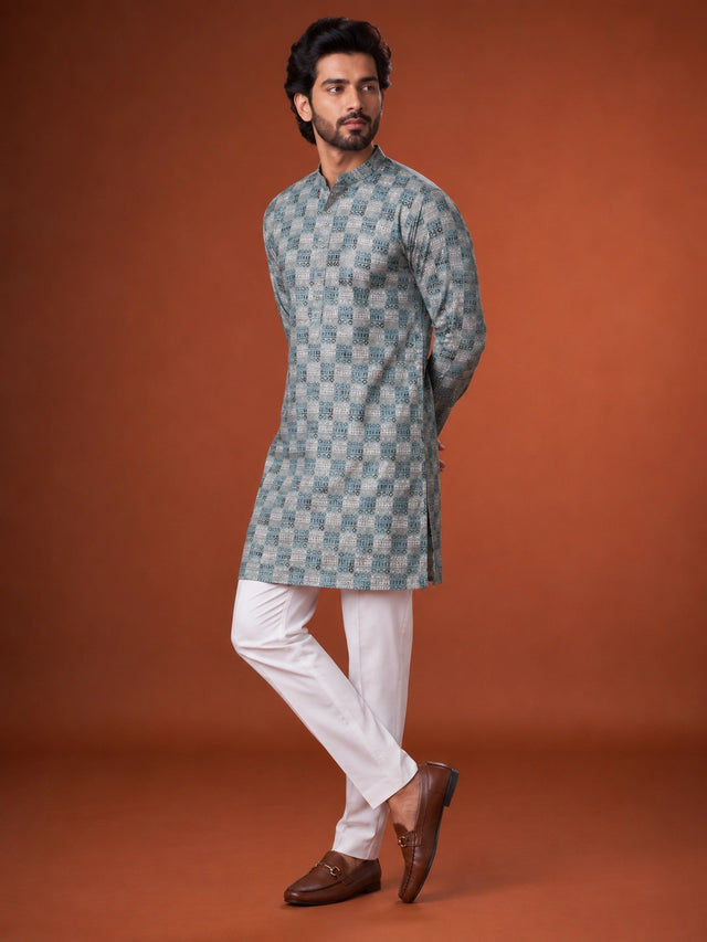 Man wearing a green and grey checkered kurta with white pajama and brown loafers.