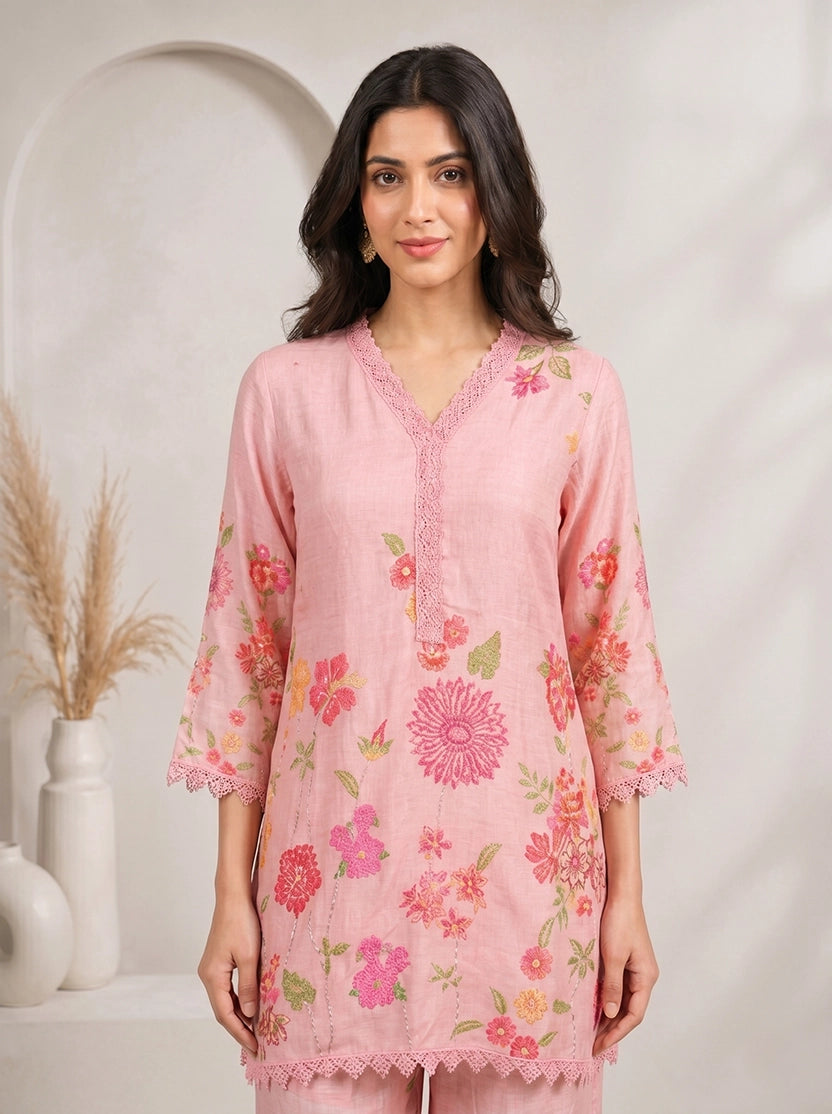 Woman wearing a pink floral print kurta with matching palazzo pants and lace trim.