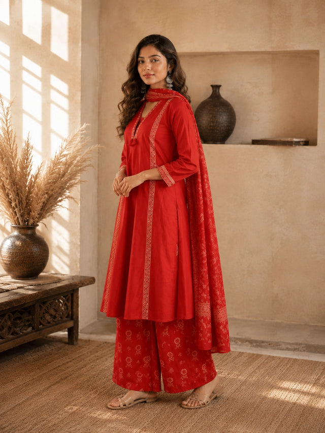 Woman wearing a rust-colored printed cotton kurti and pants set with intricate border details.