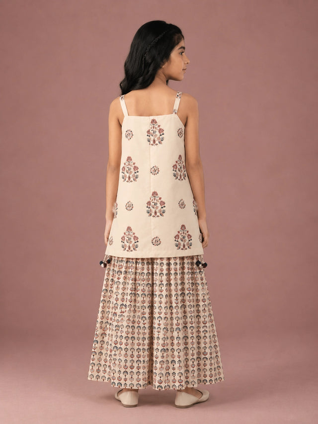 Young girl in a cream floral print strappy top and matching flared sharara set.