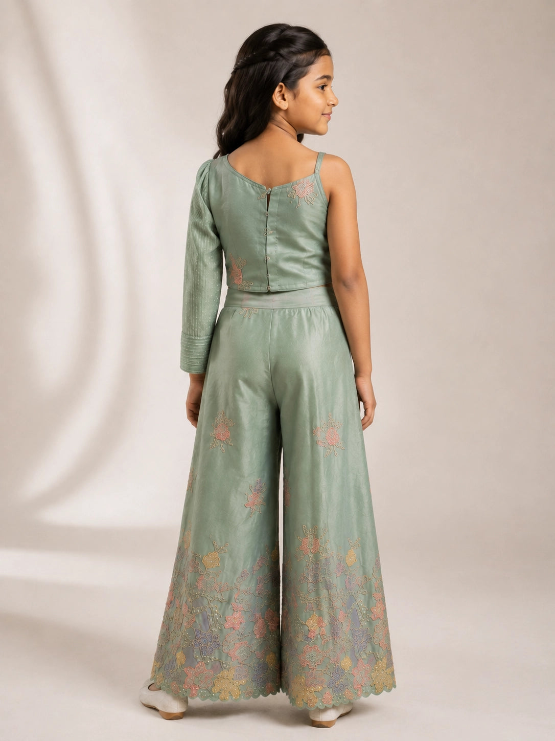 Young girl wearing a green embroidered one-shoulder palazzo set with a matching dupatta.