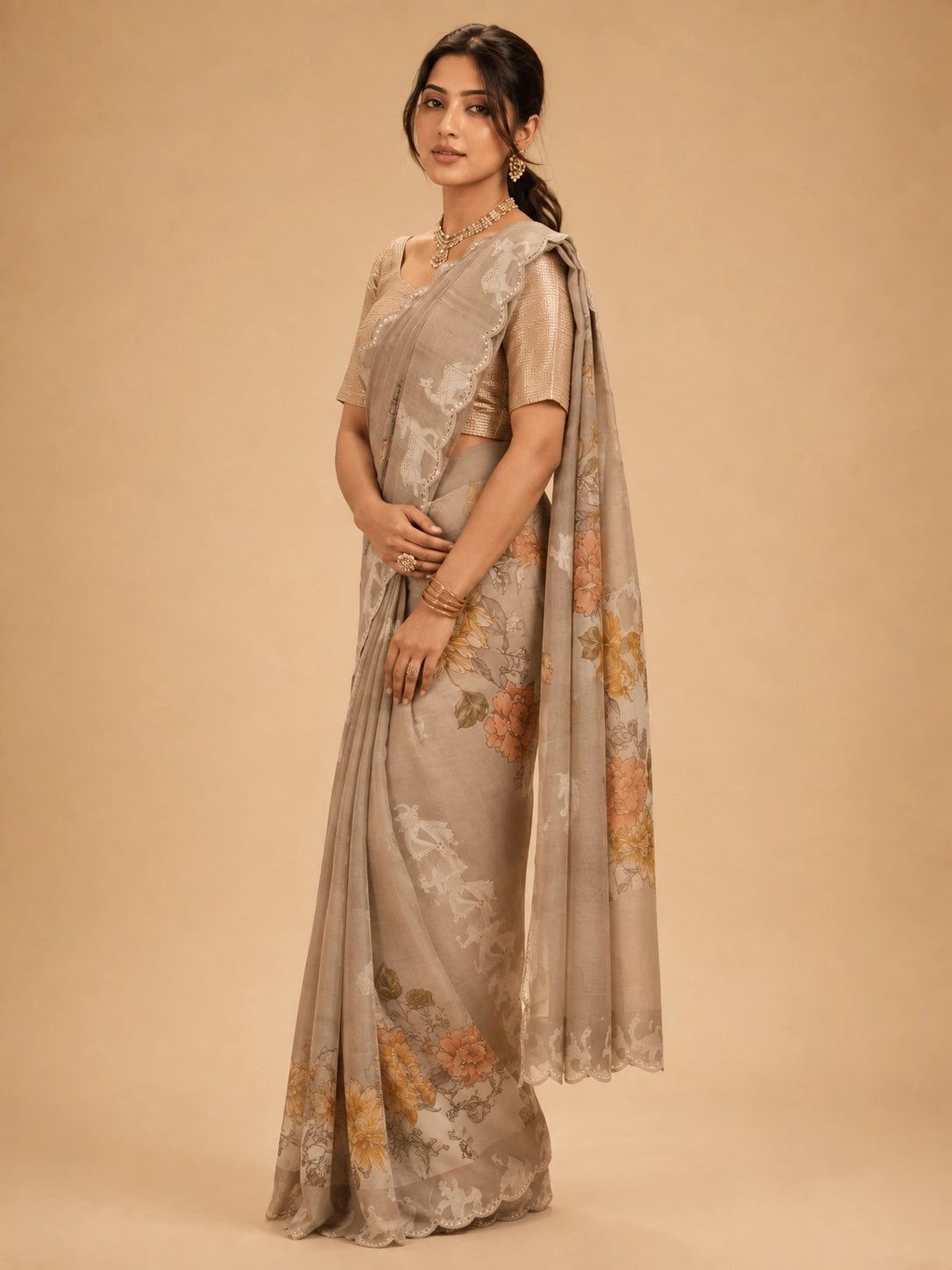 Woman wearing an elegant  peach floral saree with animal motifs and a golden blouse.
