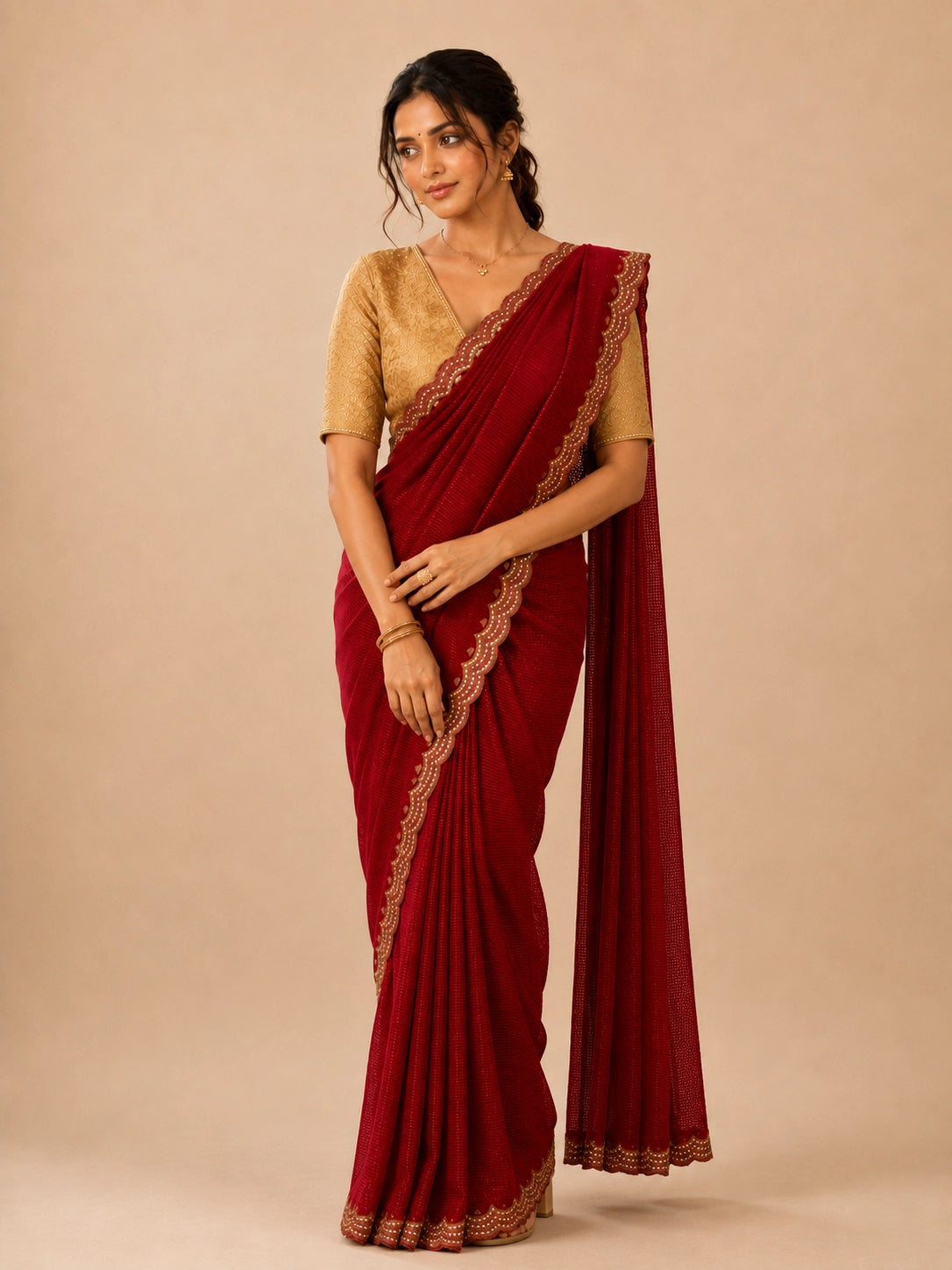 Woman in elegant red pleated saree with embellished border and golden blouse.