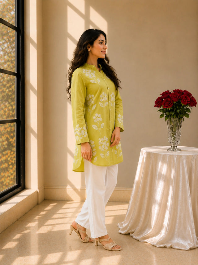 Woman in pista green embroidered tunic kurti and white trousers, smiling.