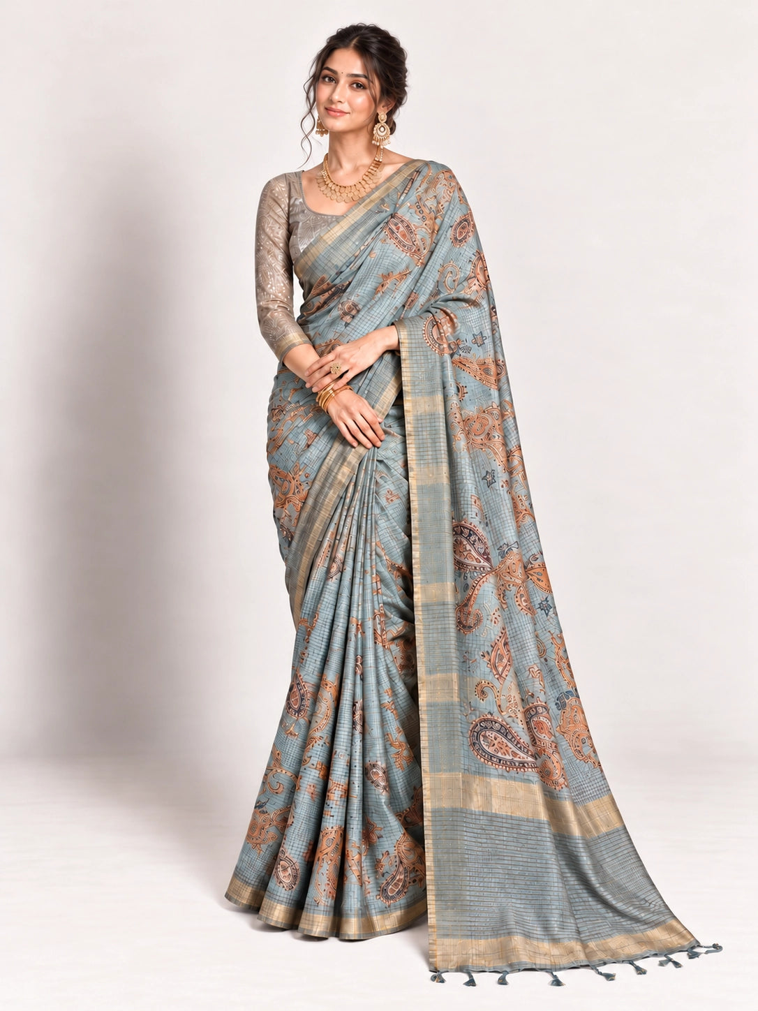 Woman in an elegant lavender grey saree with gold border and intricate paisley patterns.