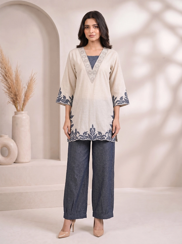 Woman wearing a beige embroidered V-neck kurta with dark blue palazzo pants, styled for a casual occasion.