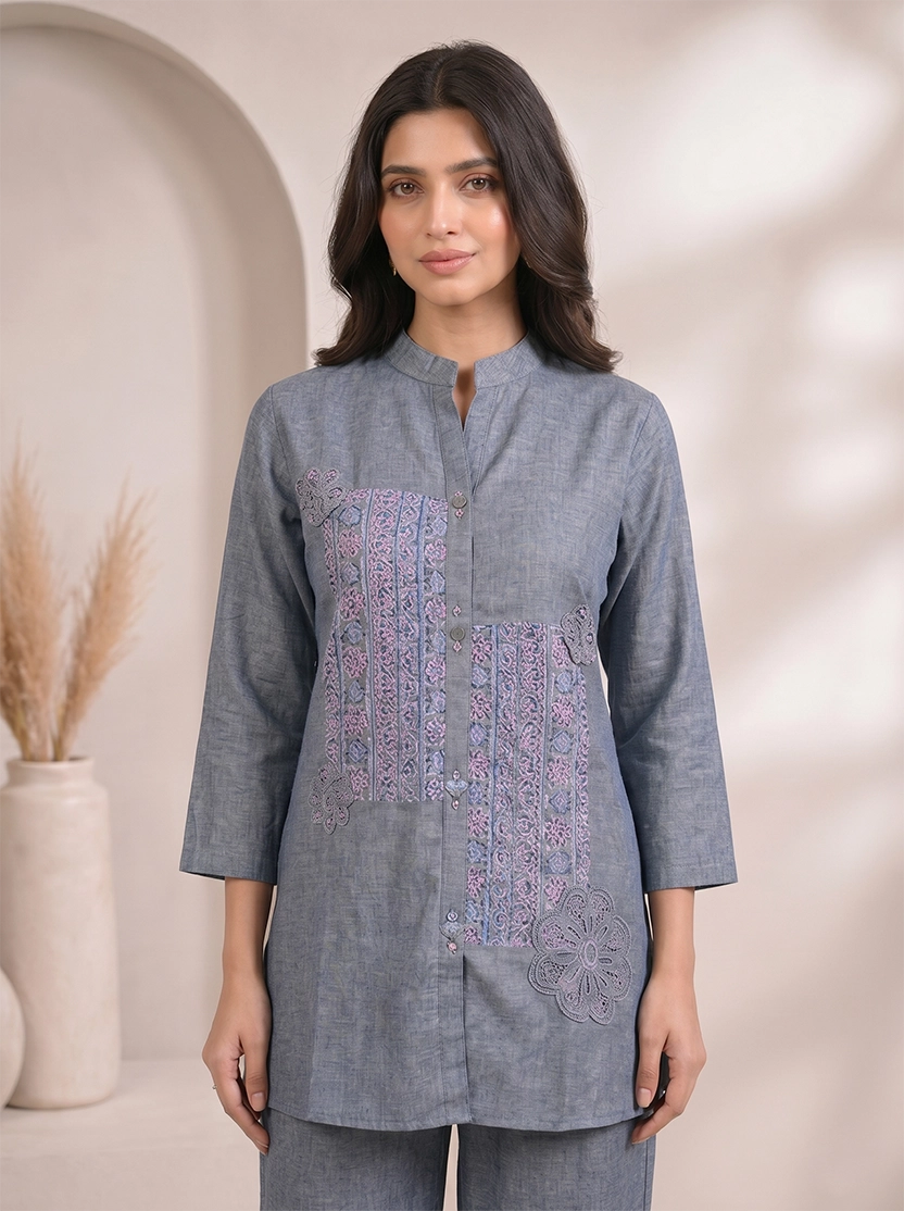 Woman wearing a blue cotton co-ord set with embroidered details on the top and straight-leg pants.