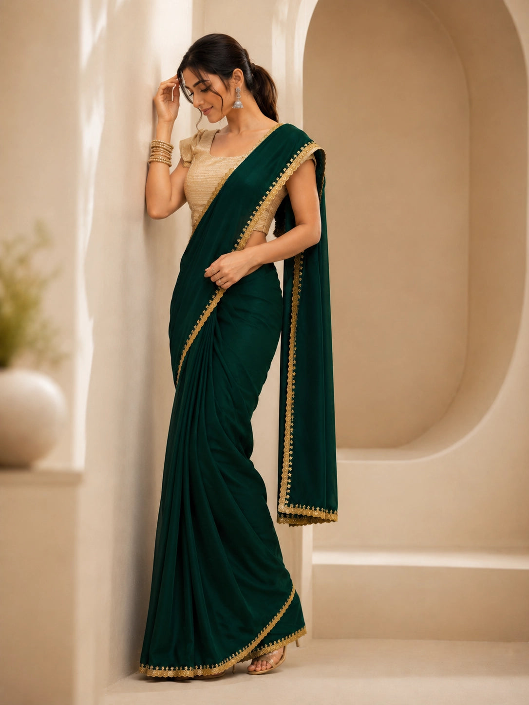 Woman wearing a beautiful emerald green saree with a golden border and matching blouse.