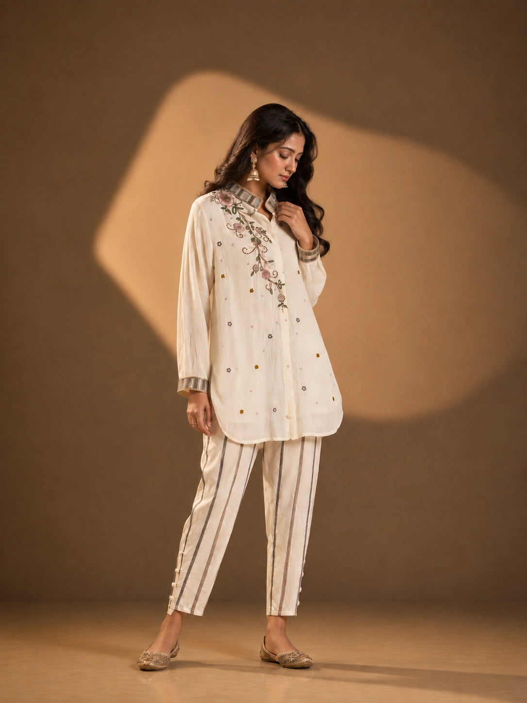 Woman wearing an elegant cream embroidered button-down kurti with striped collar and cuffs.