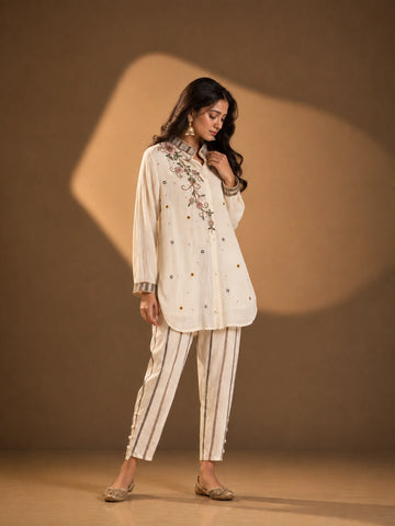 Woman wearing an elegant cream embroidered button-down kurti with striped collar and cuffs.