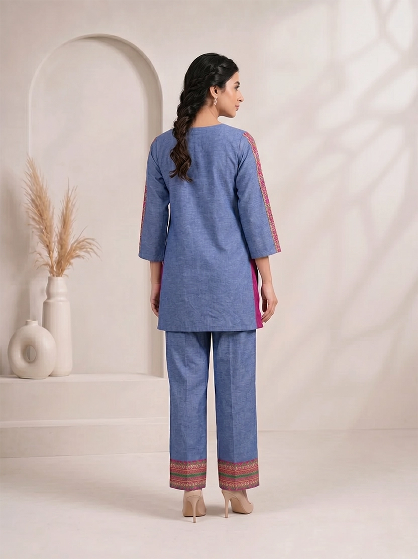 Woman wearing a blue embroidered kurta and matching wide-leg pants with a geometric border, styled with nude heels.