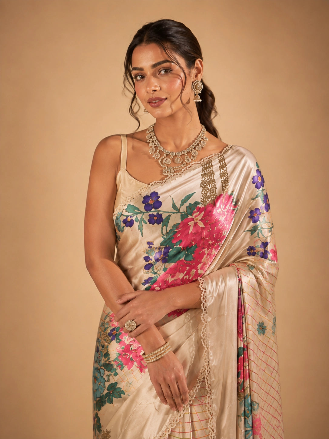 Woman in elegant cream floral saree with vibrant pink and purple flowers