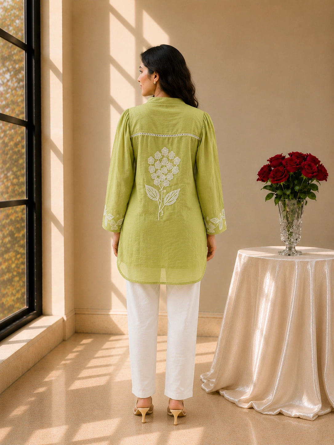Woman in pista green embroidered tunic kurti and white trousers, smiling.