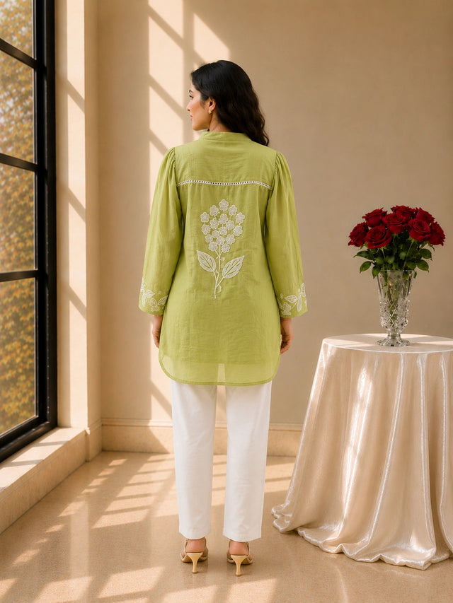 Woman in pista green embroidered tunic kurti and white trousers, smiling.