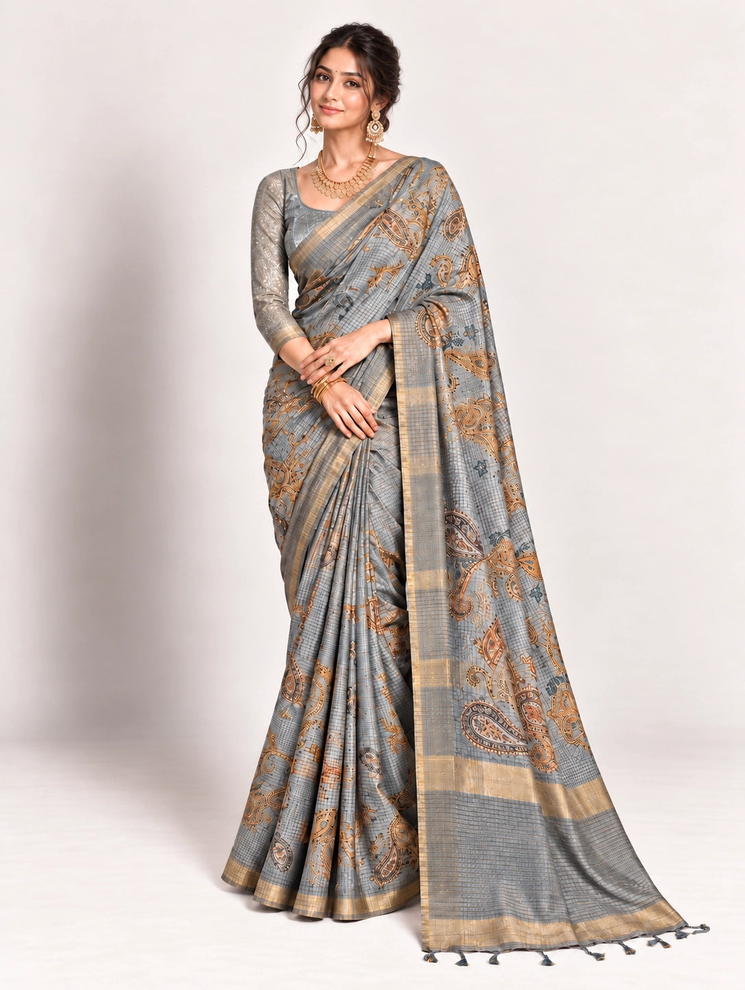 Woman in an elegant lavender grey saree with gold border and intricate paisley patterns.