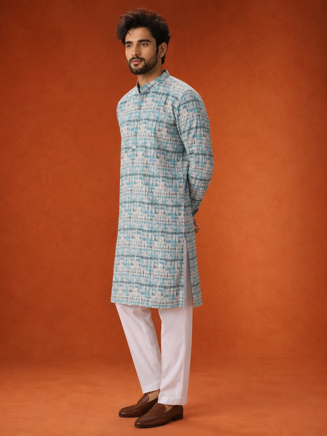 Man wearing an aqua and white printed kurta with white pajamas and brown loafers.
