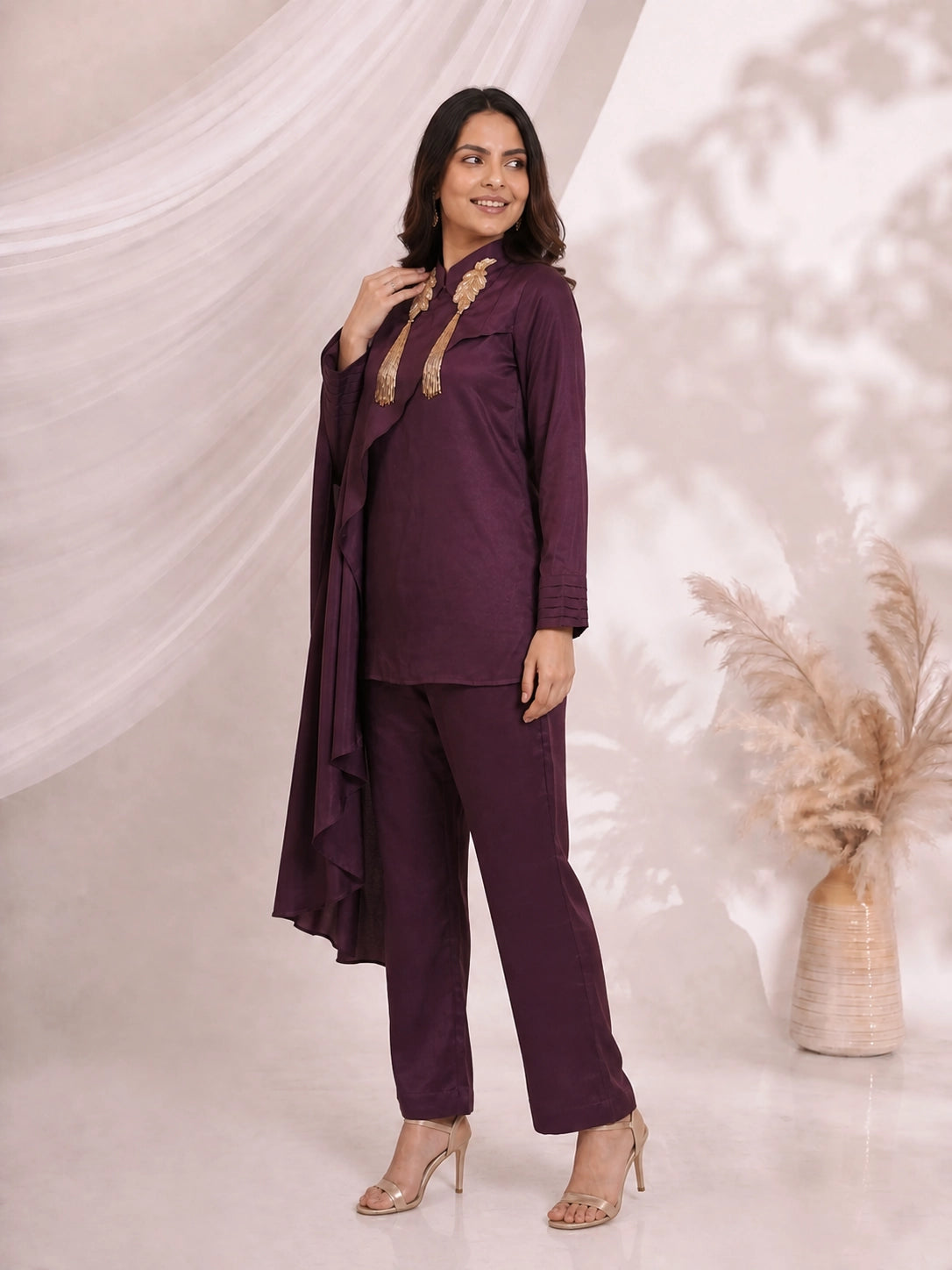 Woman wearing an elegant plum satin cape top and matching pants, styled for an evening event.