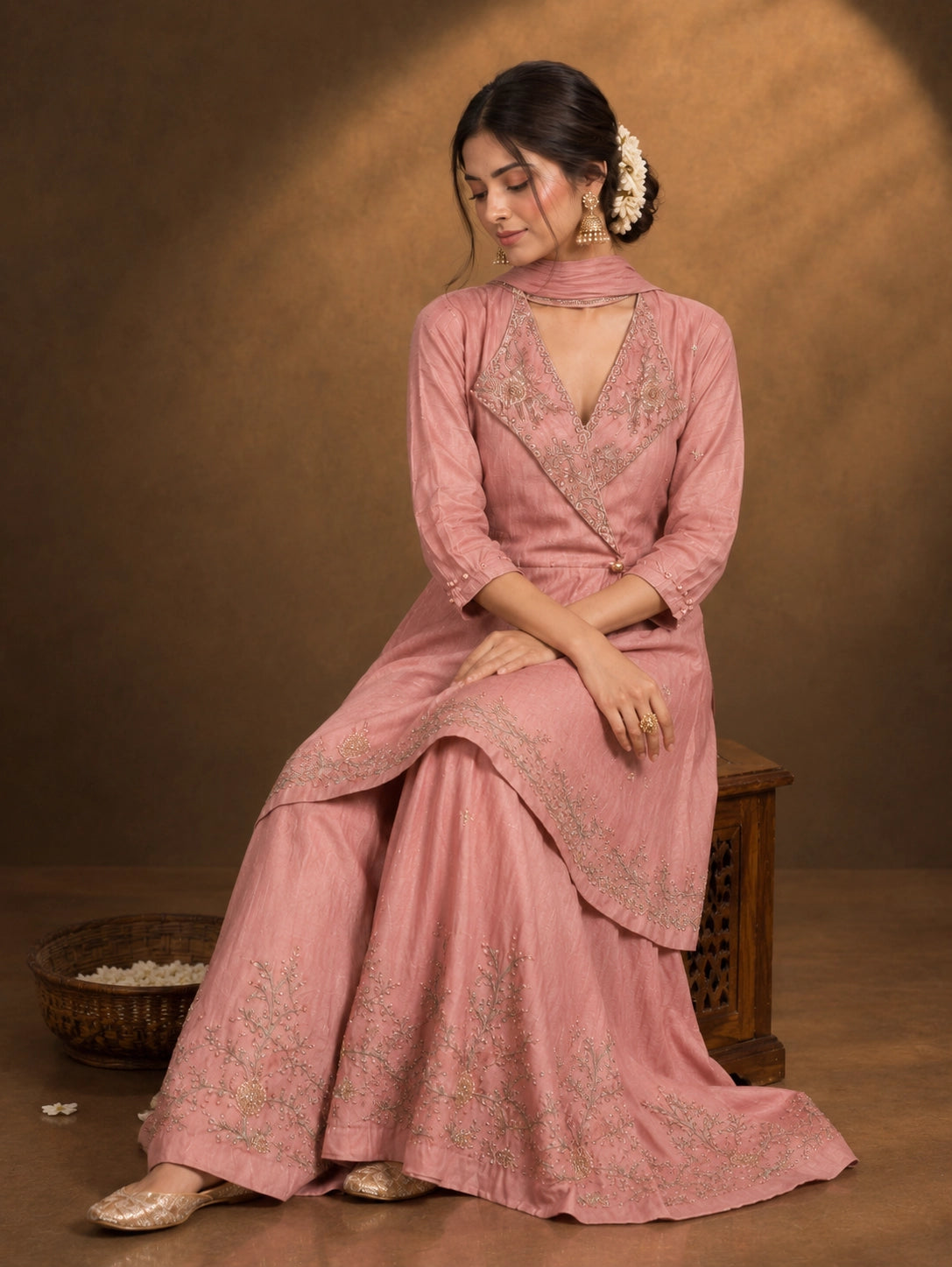 Woman in an elegant pink angrakha kurti and sharara set with intricate gold embroidery.