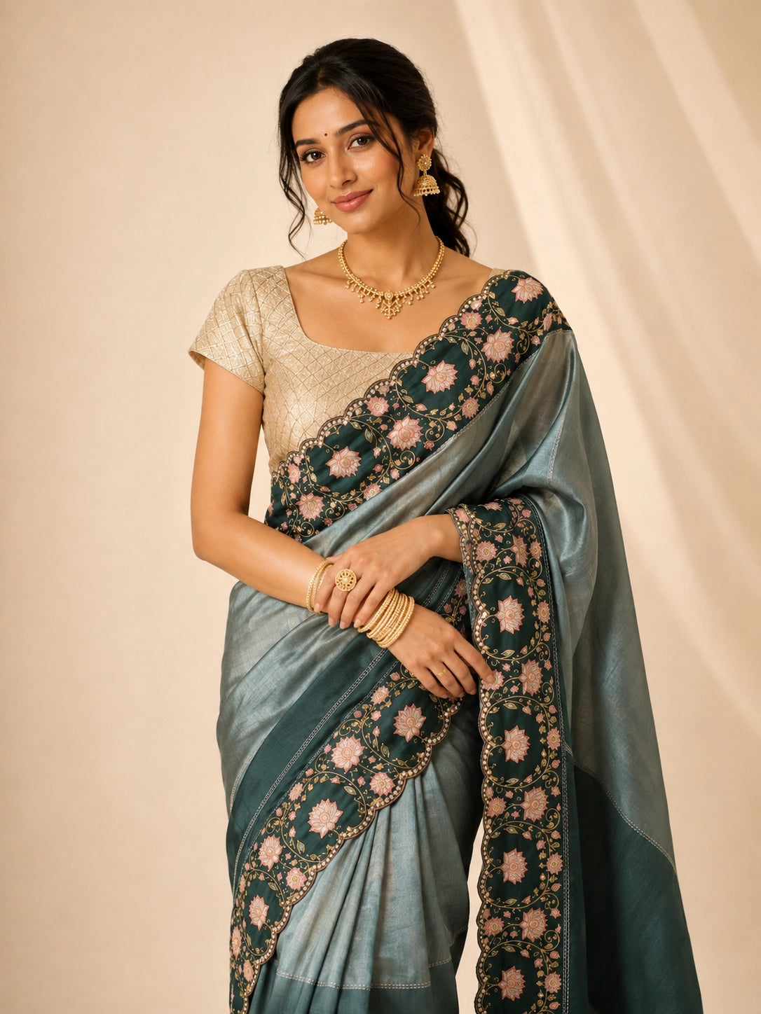 Woman wearing an elegant green embroidered saree with a golden blouse and traditional jewelry.